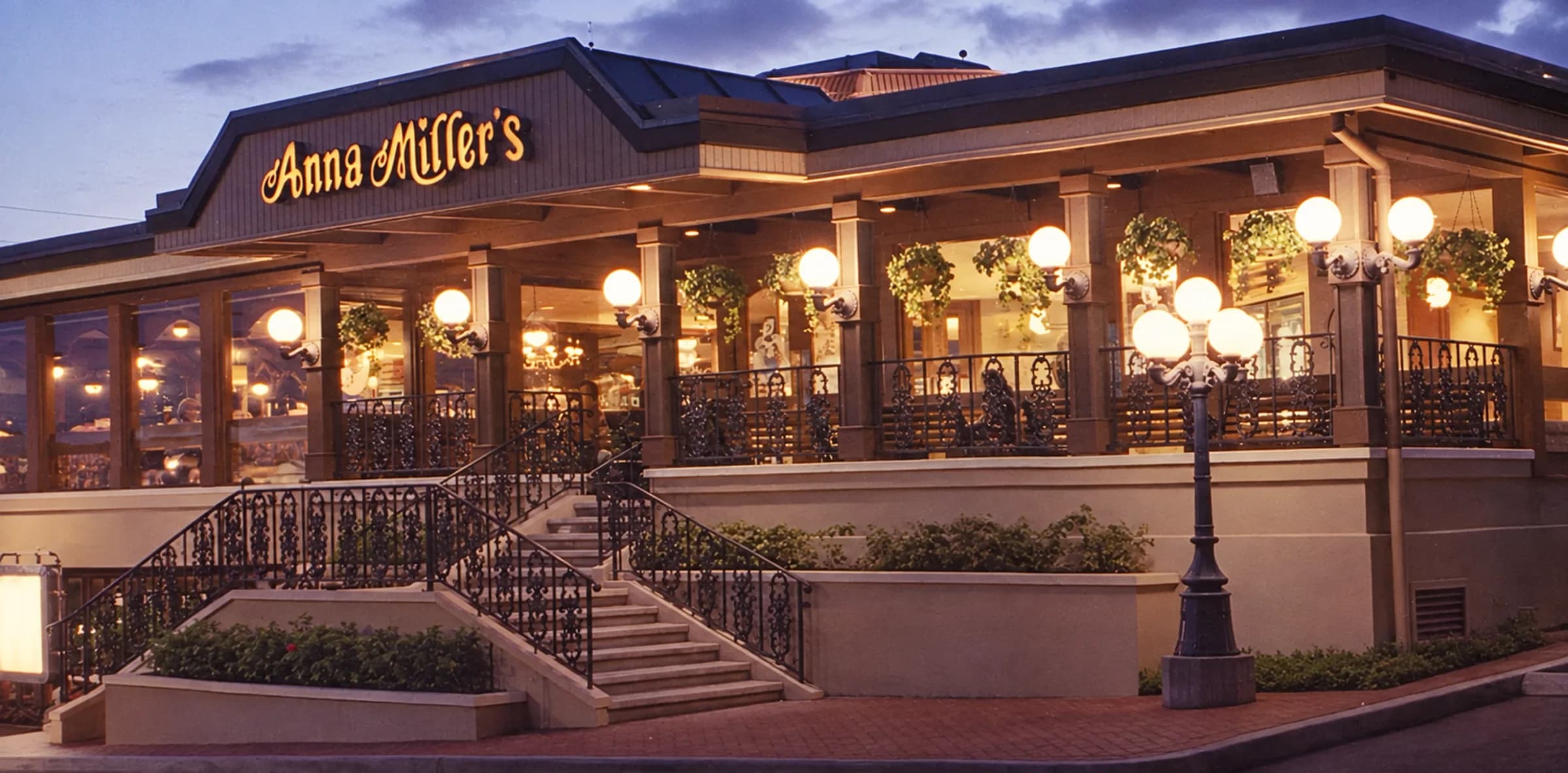 Anna Miller's at Pearlridge at dusk, the sign lit and the windows glowing