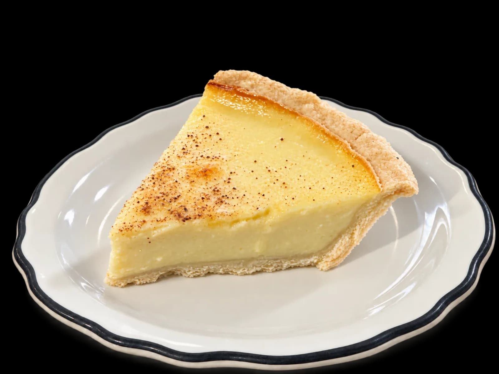 A slice of custard pie on a black-rimmed dessert plate