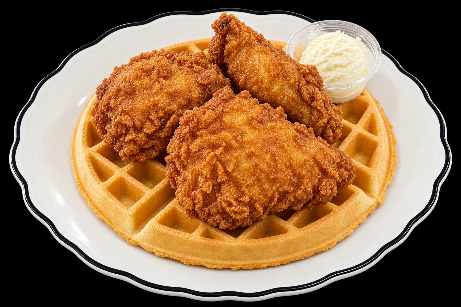 Fried chicken breast, thigh and wing on a golden Belgian waffle with a cup of whipped butter