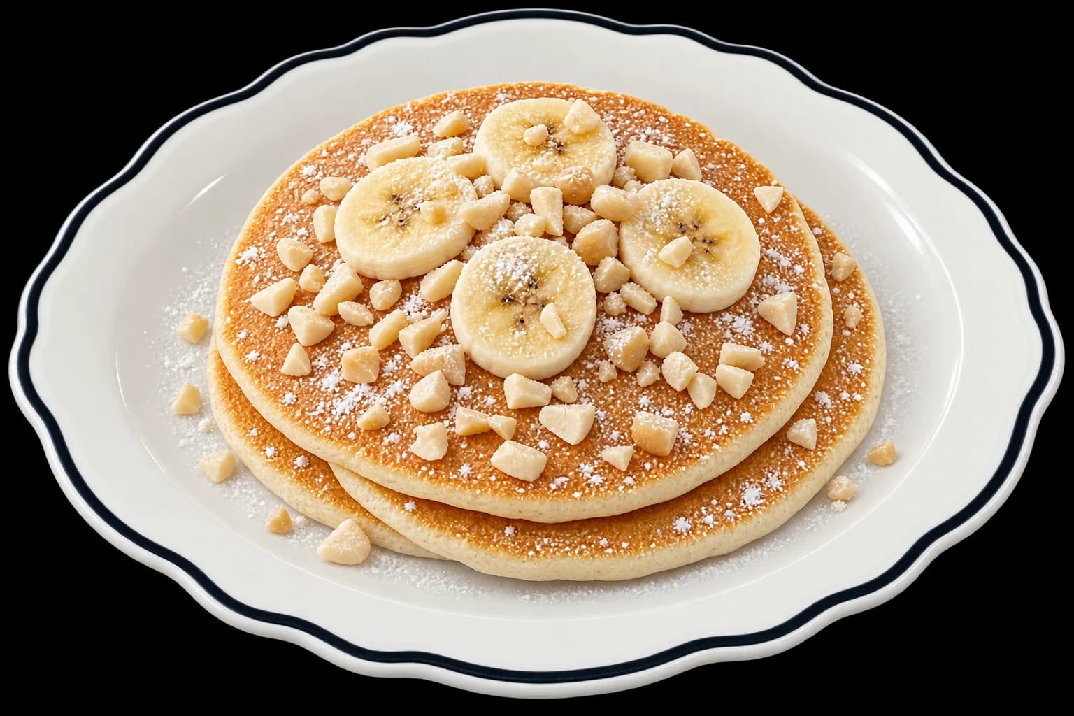 Three stacked pancakes topped with sliced banana, chopped macadamia nuts and powdered sugar